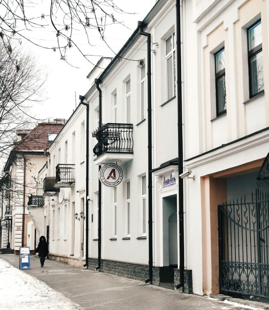 A person walks down a snowy street lined with buildings.